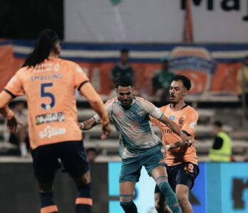 شعار النادي الأهلي السعودي مع صورة لحكم كرة قدم في ملعب.